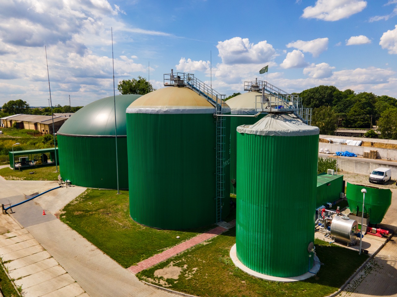 Biogaz, zdjęcie przedstawia widok z lotu ptaka na nowoczesną biogazownie, wokół pola uprawne, lasy i tereny zielone.